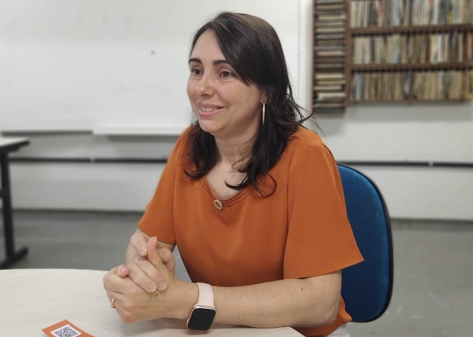 Fotografia em que aparece a professora Luciana dentro da biblioteca da ESEBA, UFU.